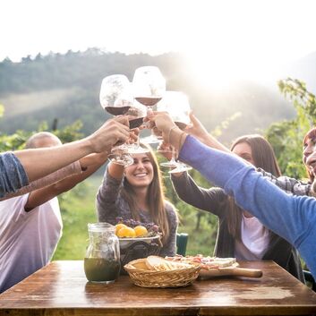 Five people holding red wine glasses in an Okanagan vineyard
